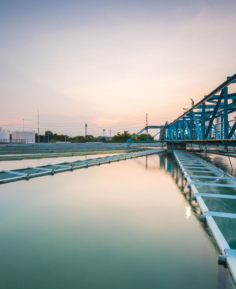 Grande installation de traitement des eaux avec des structures bleues et des eaux calmes au coucher du soleil